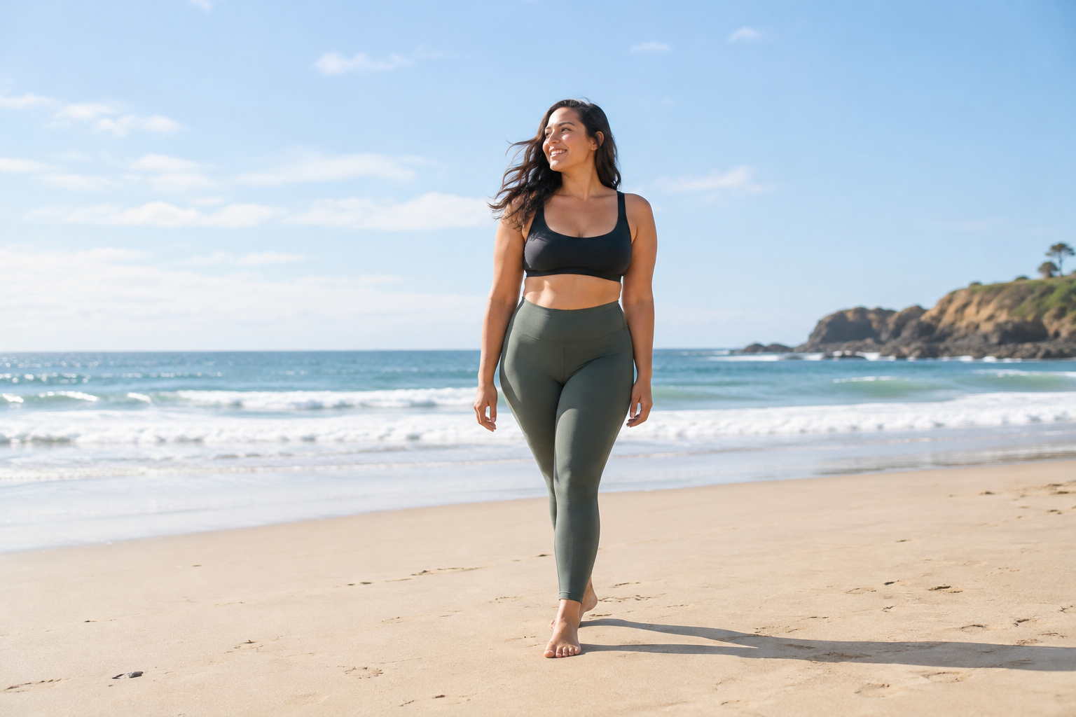 A woman looking confident while wearing leggings at the beach, enjoying the sun and sand.